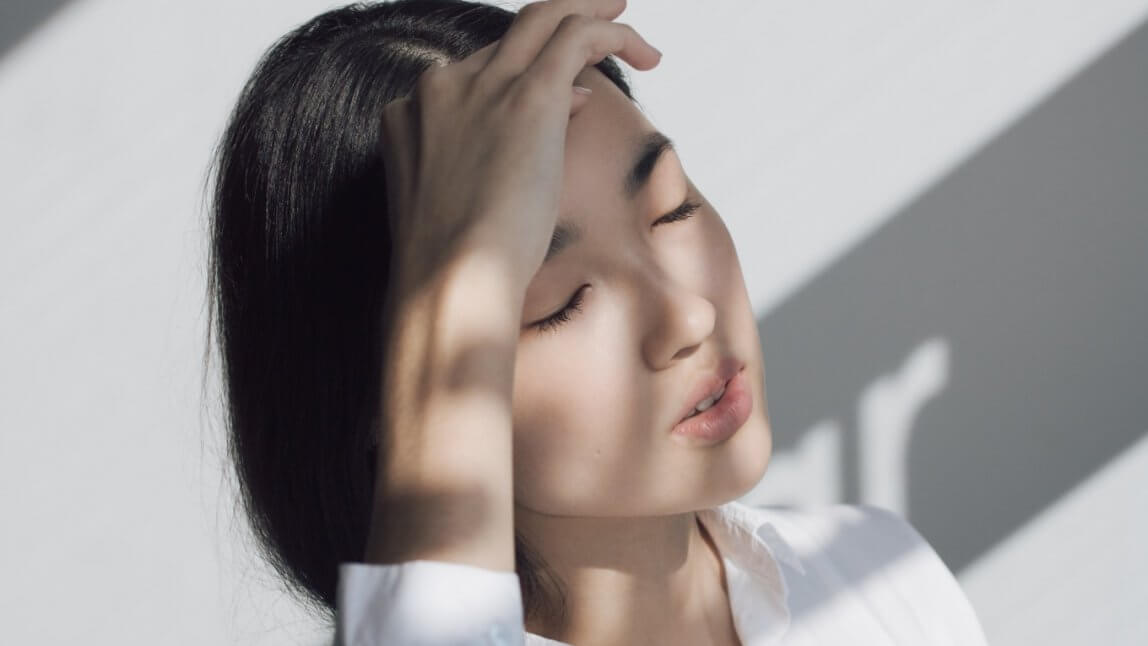Woman with her eyes closed and massaging her forehead.
